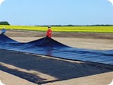 Once the geotextile matting is placed, the crew begins unfolding the liner.